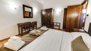 Une chambre d’hôtel avec un grand lit, des meubles en bois, une armoire et un miroir.