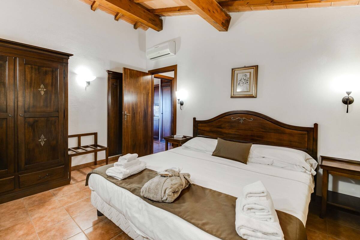Ein Hotelzimmer mit einem hölzernen Bett, einem Kleiderschrank und einem Nachttisch.