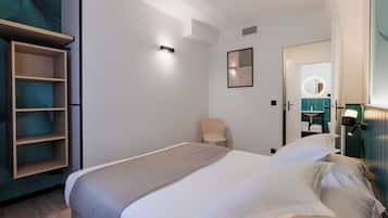 Una habitación de hotel moderna con una cama bien hecha, una silla y un armario con estantes.