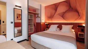 A modern hotel room with a large bed, a bedside table, a wardrobe, and a mirror.