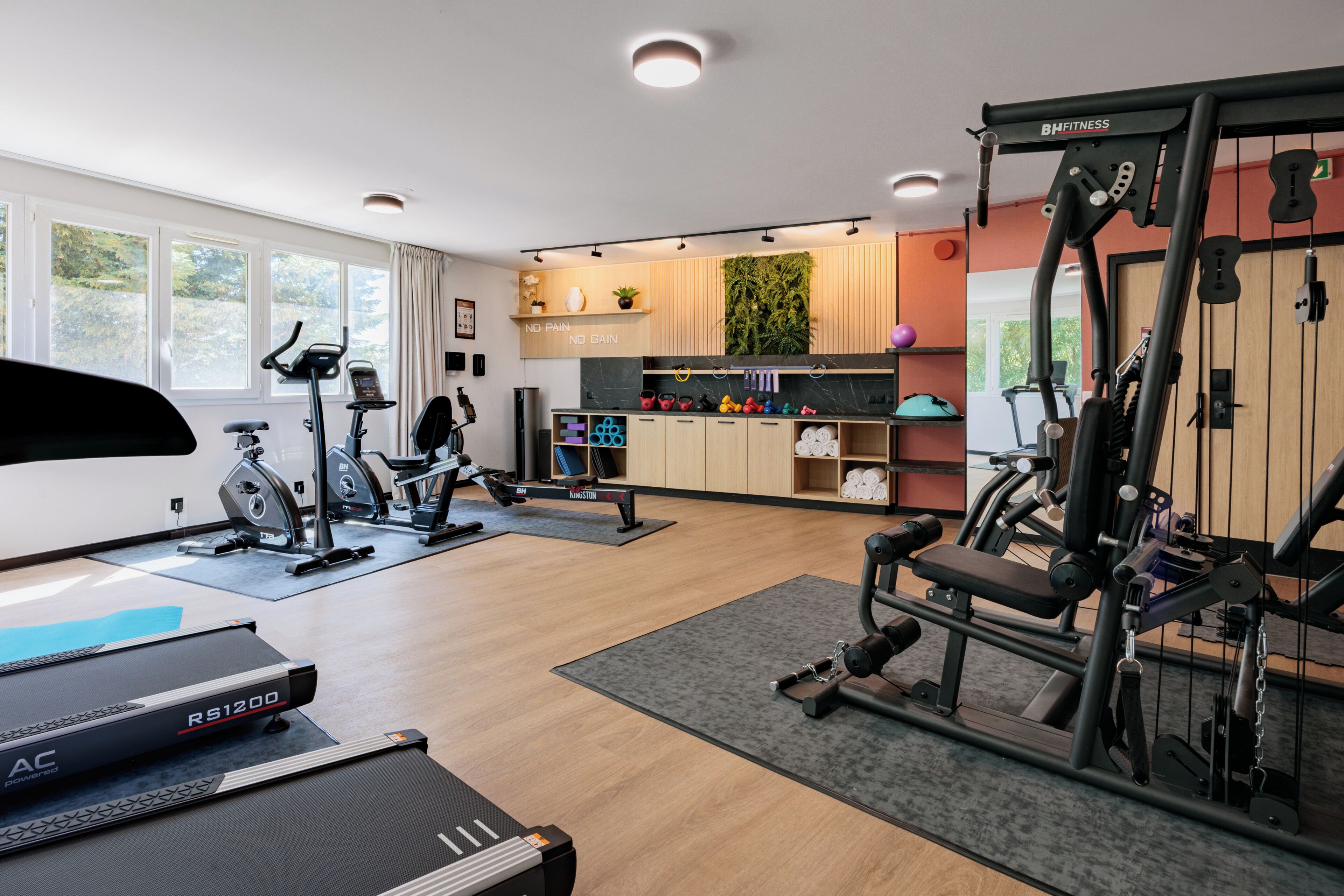 Un gimnasio con máquinas de cardio, equipo de levantamiento de pesas y una cinta de correr.