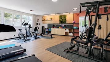 Un gimnasio con máquinas de cardio, equipo de levantamiento de pesas y una cinta de correr.