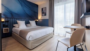 Et moderne hotelværelse med en stor seng, et skrivebord og et fjernsyn.