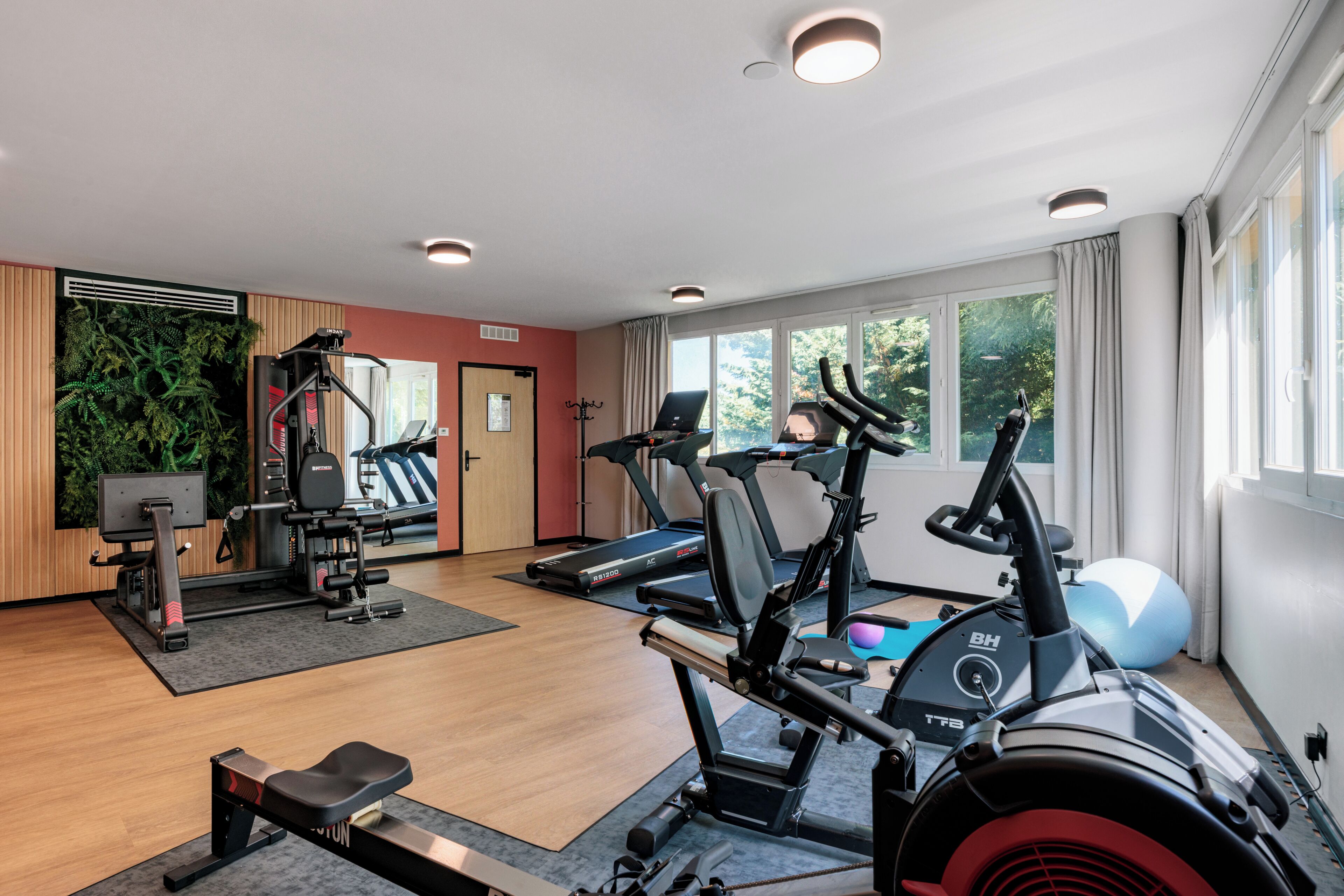 A gym with cardio machines, a rowing machine, and a weight bench.