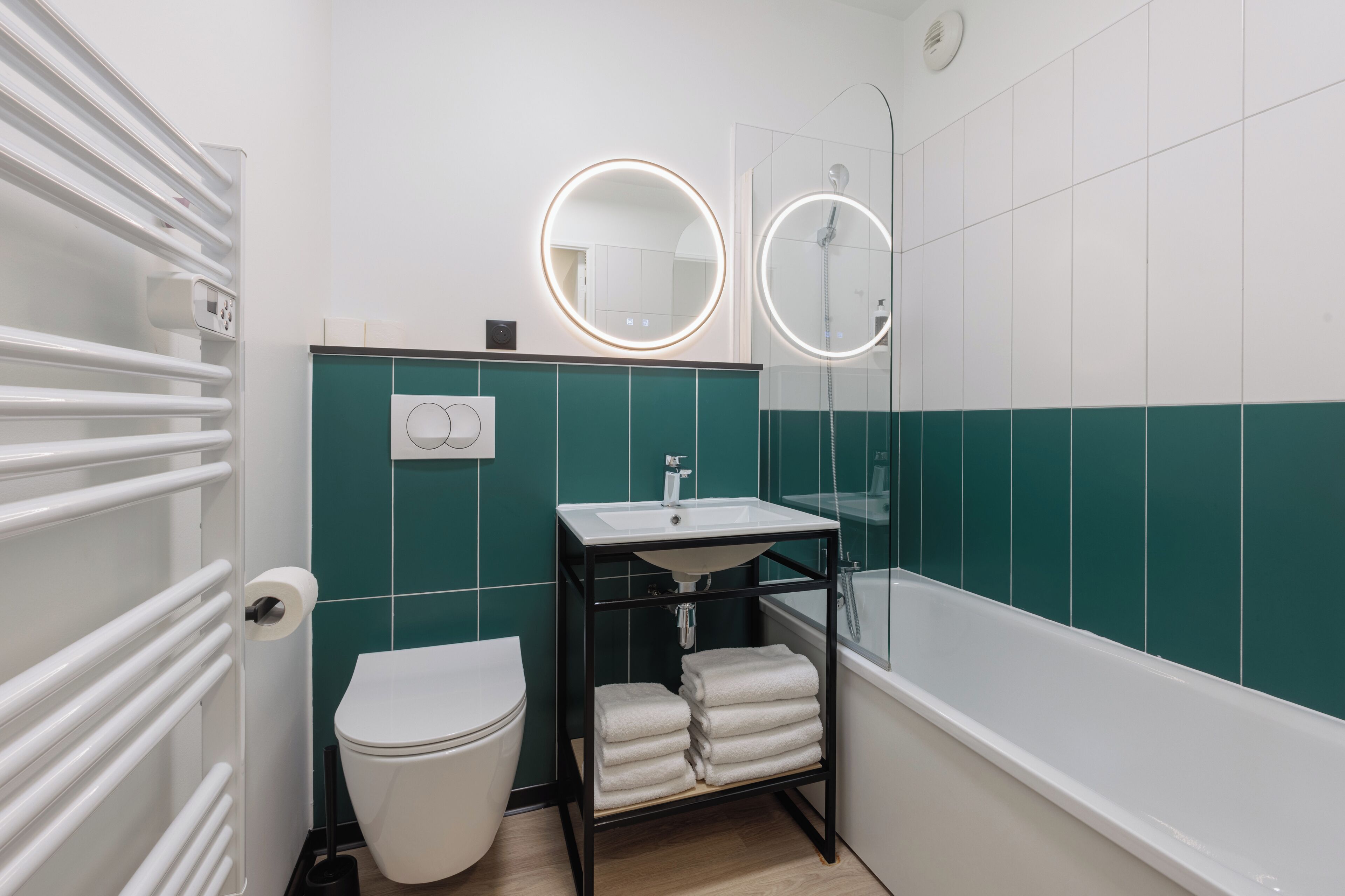 A modern bathroom with a white toilet, a sink with a mirror, and a bathtub.
