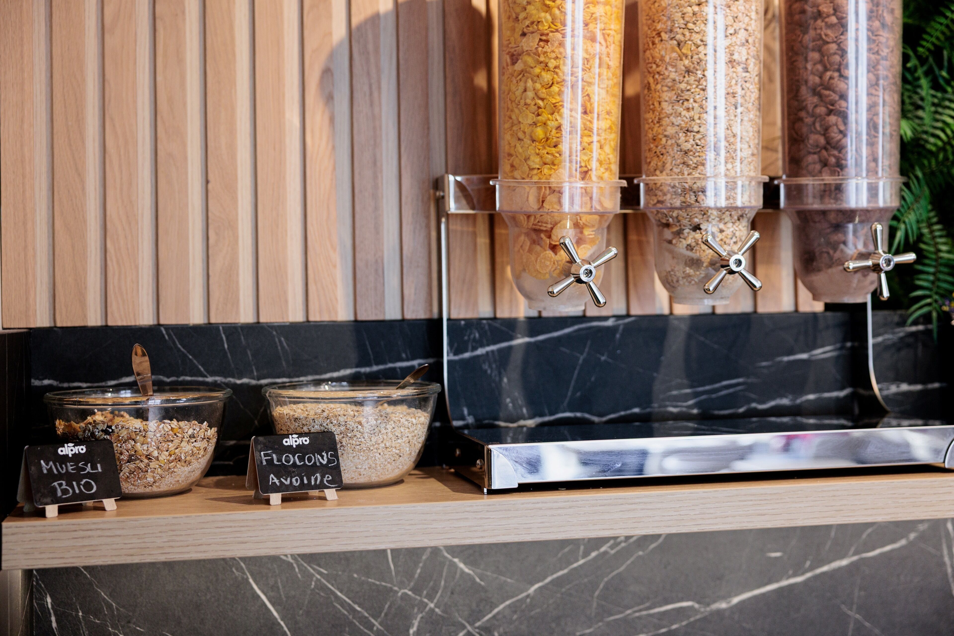 A food dispensing station with labeled containers for Muesli Bio and Flocons Avoine.