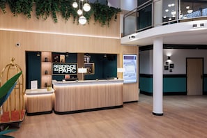 Un mostrador de recepción moderno con detalles de madera, una pantalla digital y un letrero que dice "RESIDENCE at PARC".