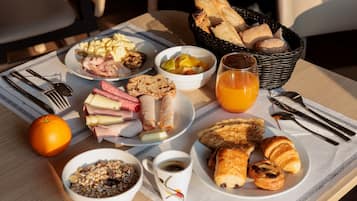 A breakfast table with various food items, including eggs, ham, bread, and a croissant.