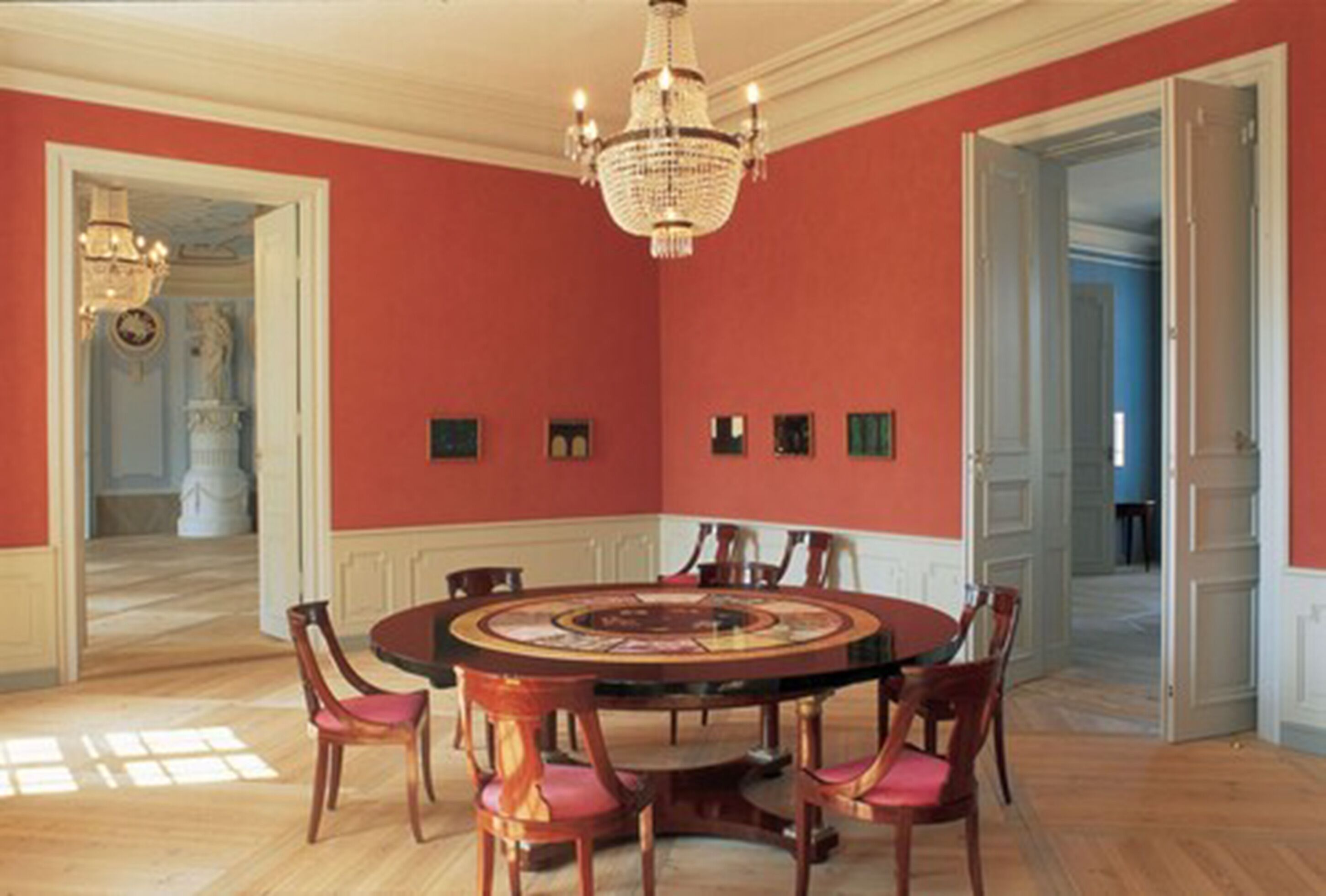 A dining room with a round table, chairs, and a chandelier.
