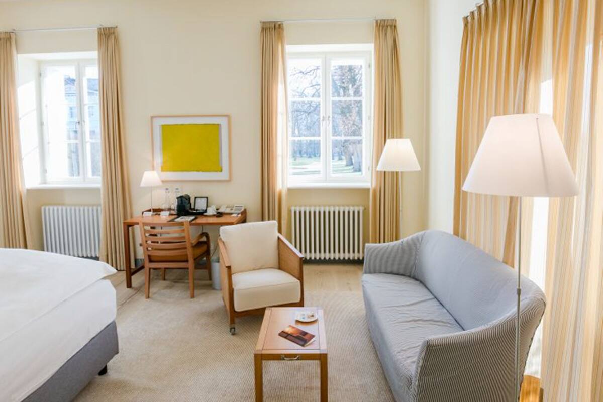 Una habitación de hotel con cama, escritorio, silla, sofá y lámpara.