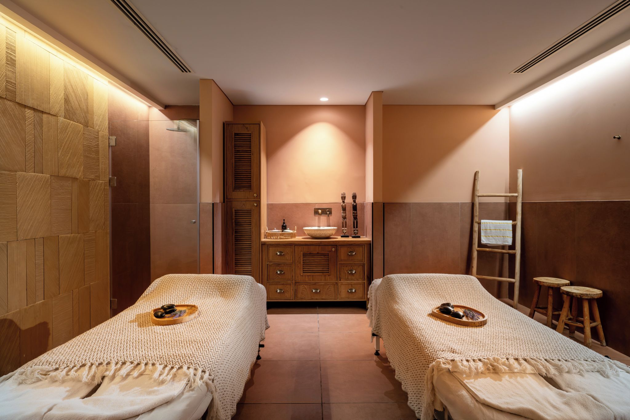 A room with two beds, a wooden cabinet, a sink, and a ladder.