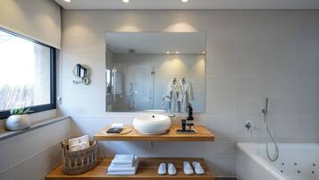 Une salle de bain moderne avec un grand miroir, un lavabo sur colonne, une baignoire et une fenêtre offrant une belle vue.