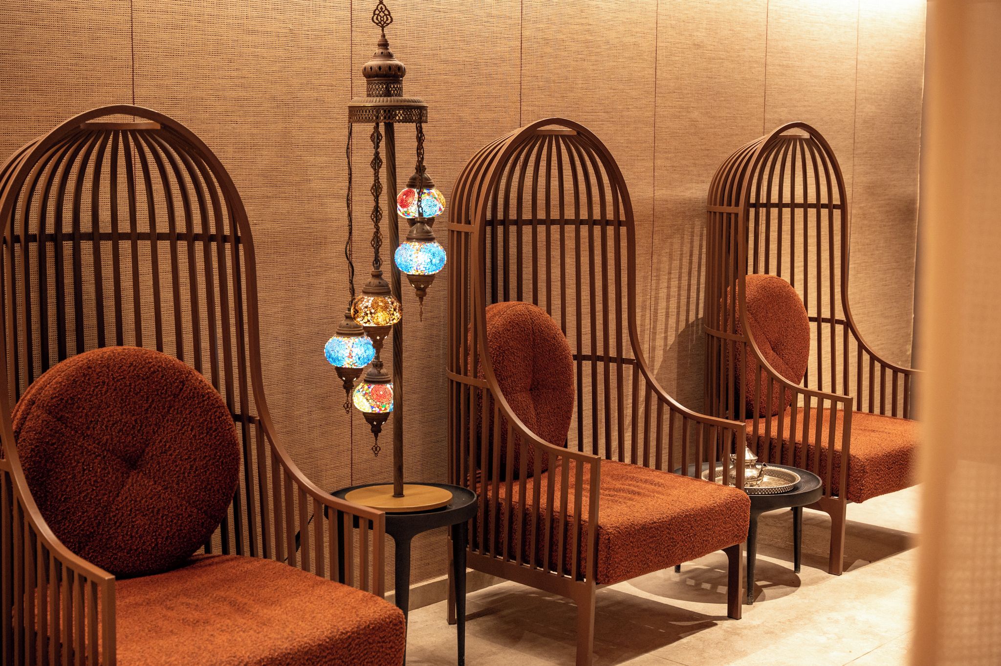 A seating area with cushioned chairs and a hanging light fixture.