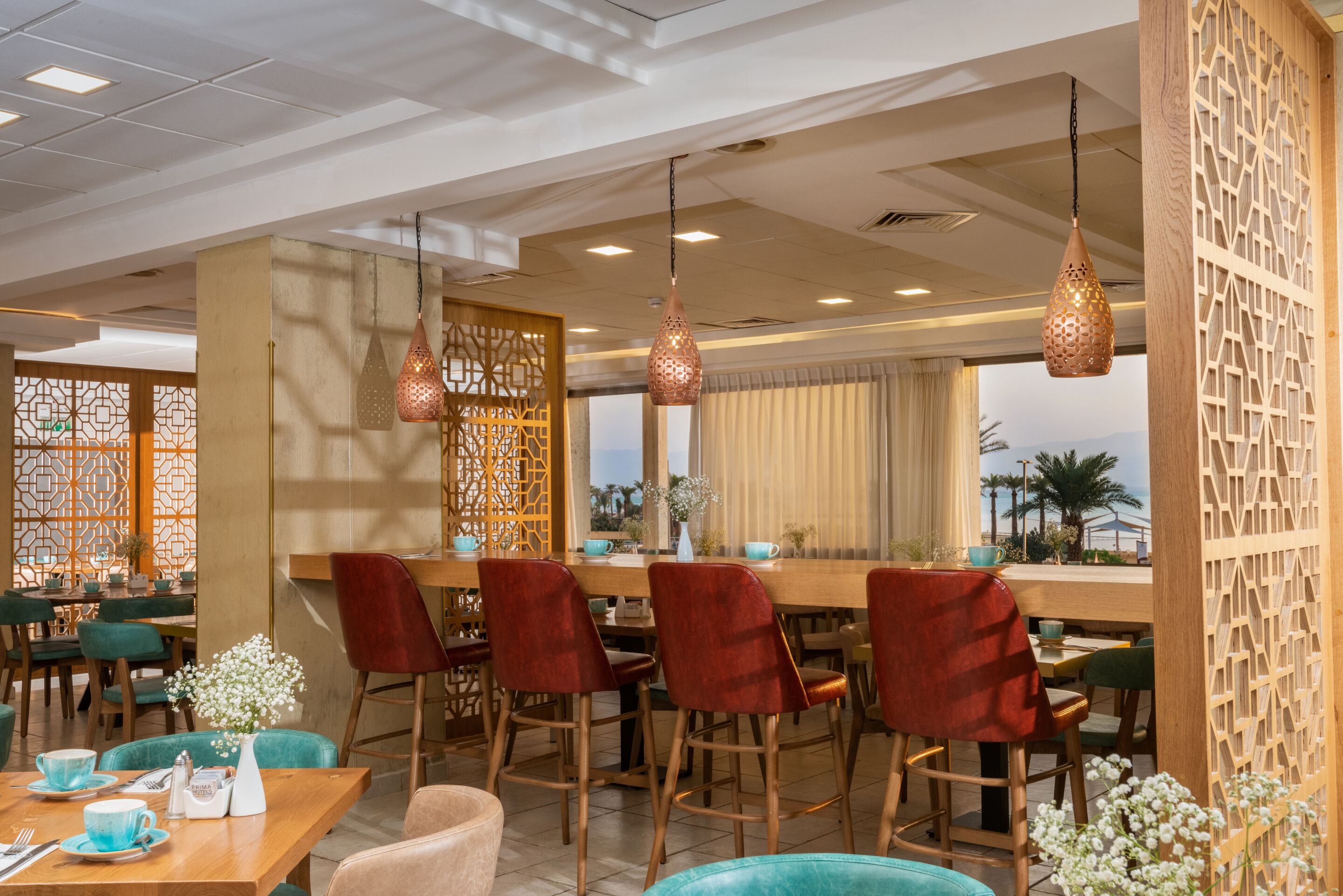 A restaurant with a bar area, red bar stools, and a view of palm trees.