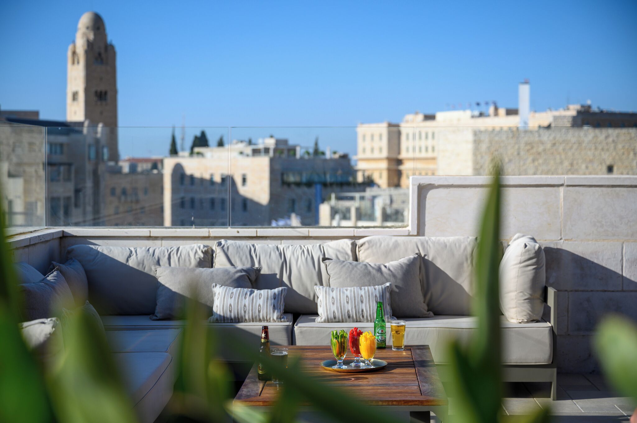 Una terraza en la azotea con sofá, una mesa con bebidas y vistas a la ciudad.