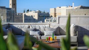Una terraza en la azotea con sofá, una mesa con bebidas y vistas a la ciudad.