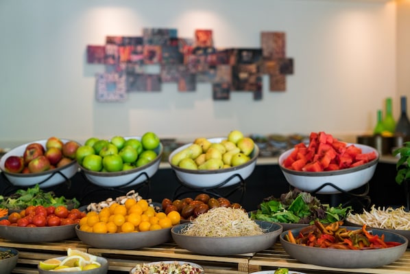 Una mesa de buffet con frutas, verduras y ensaladas variadas.