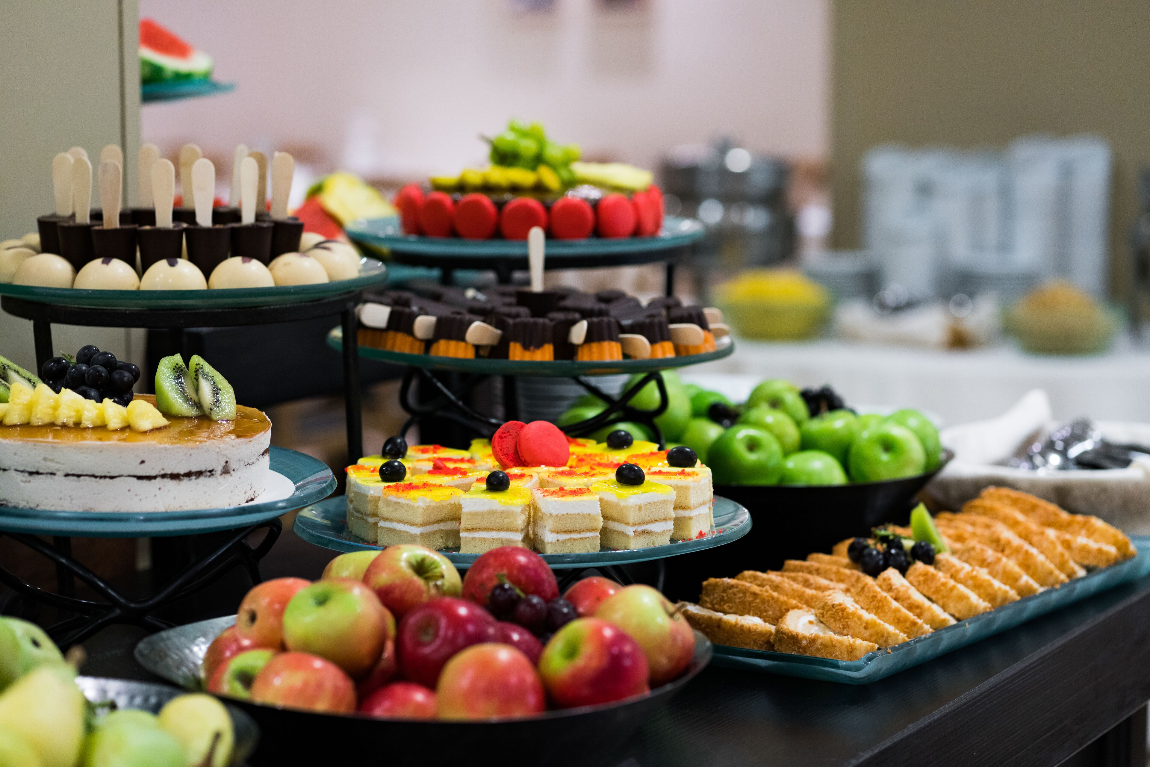 Un bufé con diversas opciones de comida, incluyendo pasteles, frutas y postres.