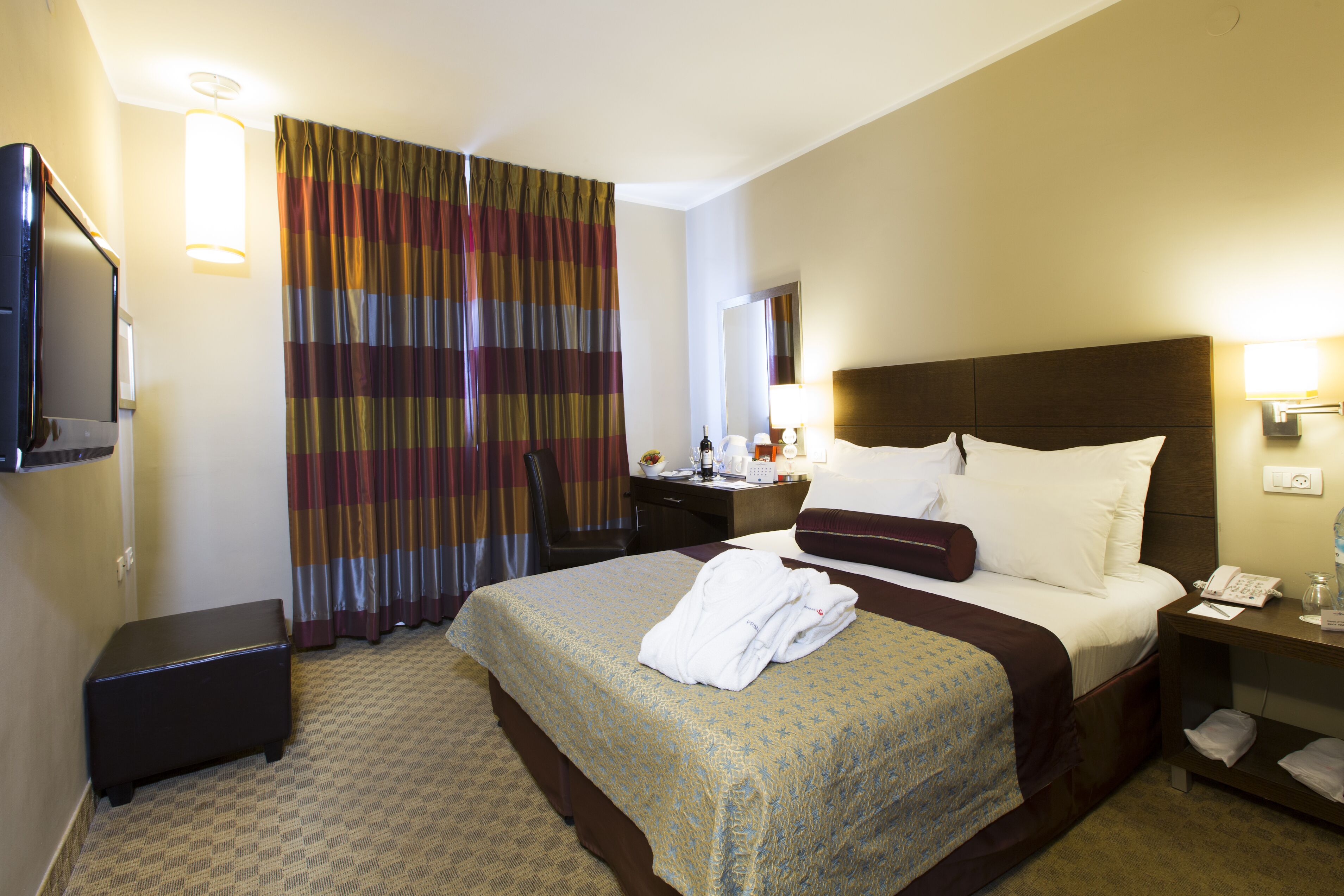 Una habitación de hotel con cama, mesita de noche, televisor y un escritorio con silla.