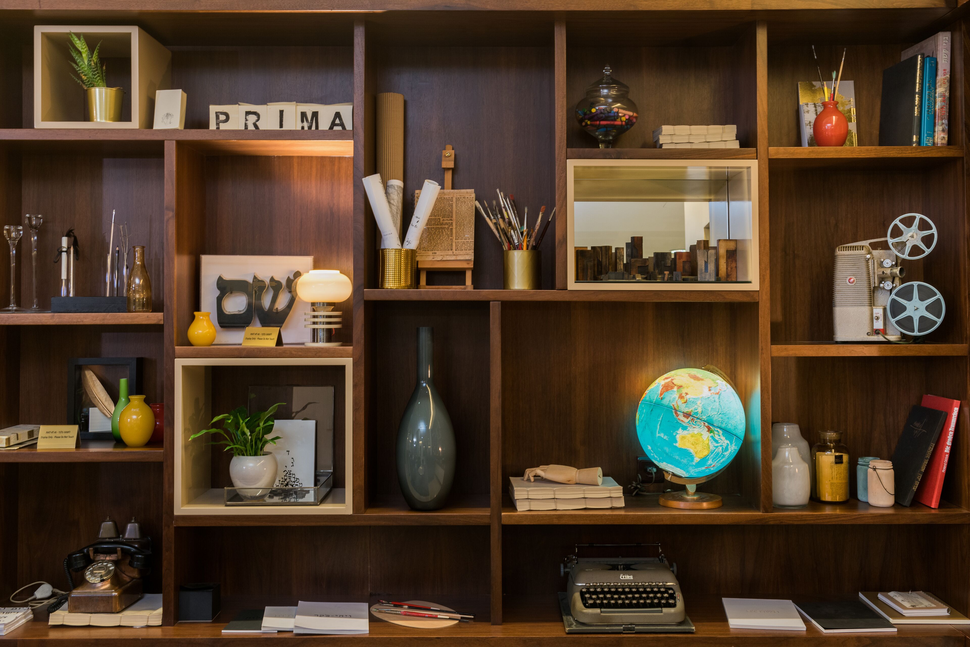 A well-organized room with wooden shelves containing books, decorative items, a globe, and a vintage typewriter.