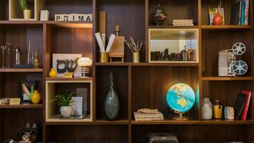 A well-organized room with wooden shelves containing books, decorative items, a globe, and a vintage typewriter.