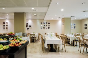 A buffet setup with various food items and a long dining table with chairs.