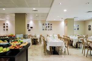 Montaje de bufé con diferentes alimentos y una larga mesa de comedor con sillas.
