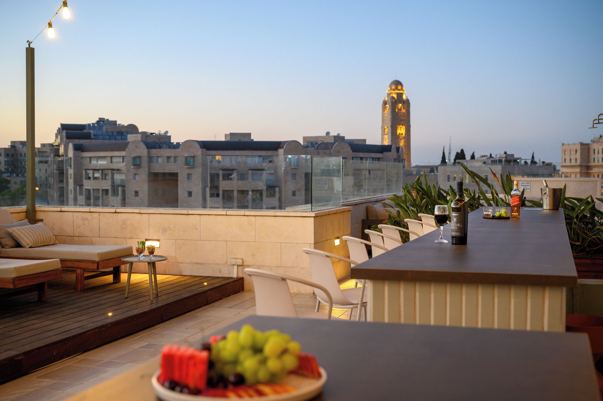 Terraço no telhado com área de bar, assentos e vista da paisagem urbana, incluindo um campanário.