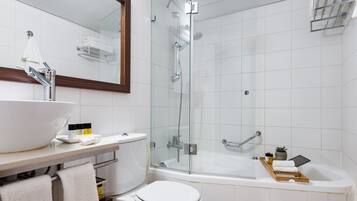 Un baño moderno con ducha envuelta en vidrio, un lavabo blanco con cuenco y un inodoro.