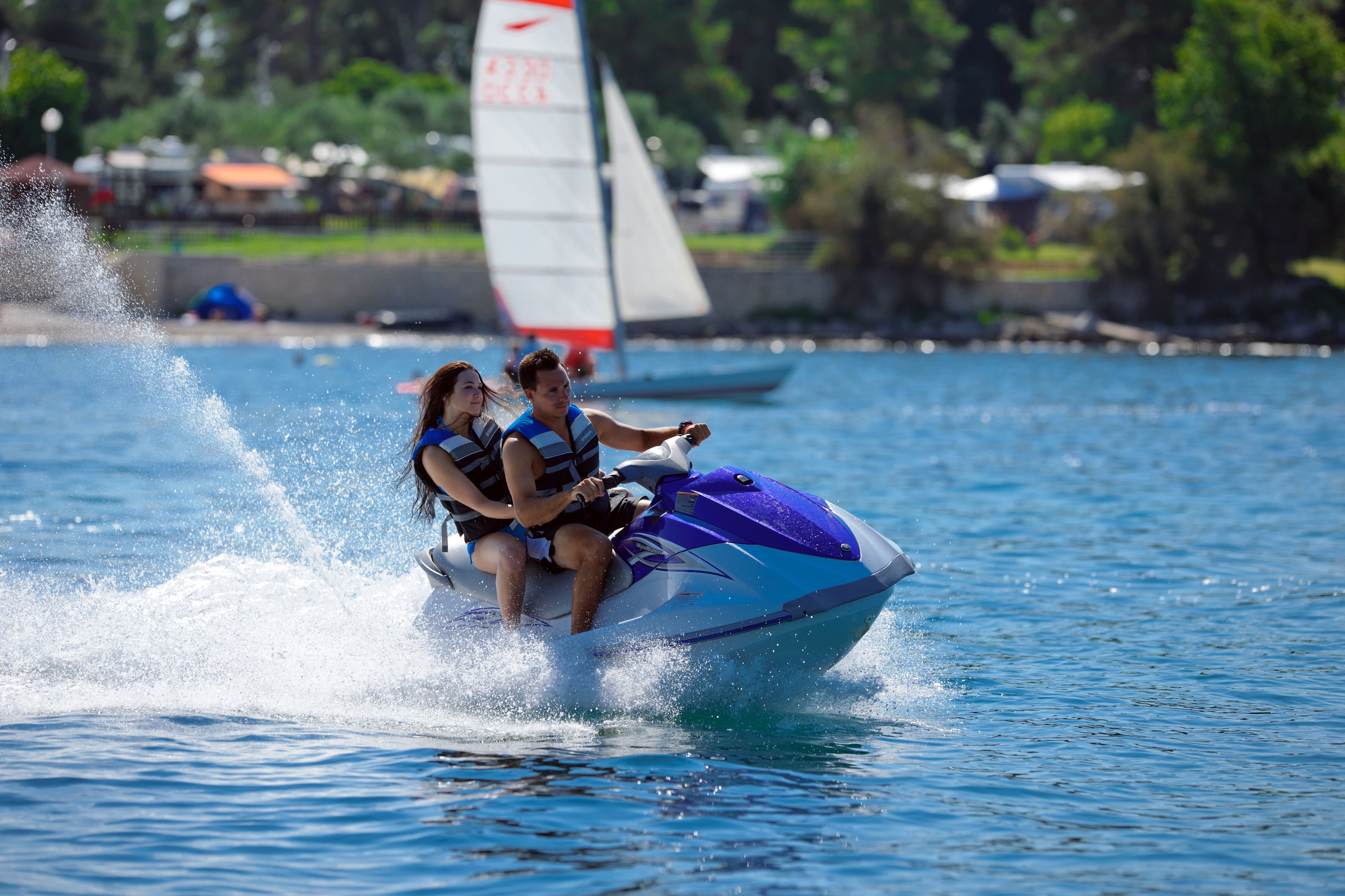 A jet ski with two people on it, moving through water.