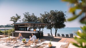 Un espace extérieur aménagé avec des chaises en osier et un bar offrant une vue sur la mer.