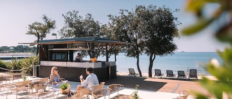 Un espacio de estar al aire libre con sillas de mimbre y una zona de bar con vistas al mar.