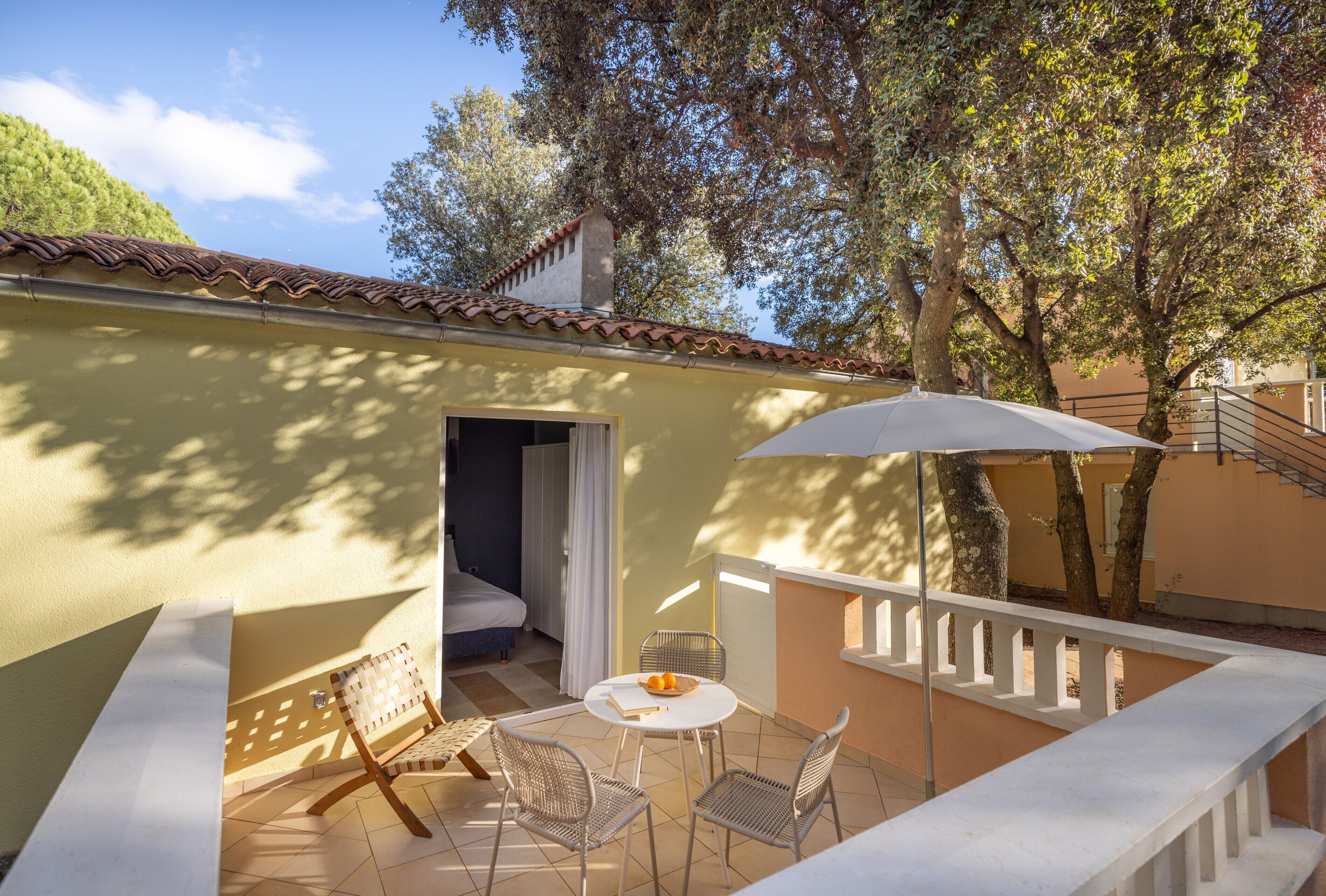 A balcony with a table, chairs, and a white umbrella.