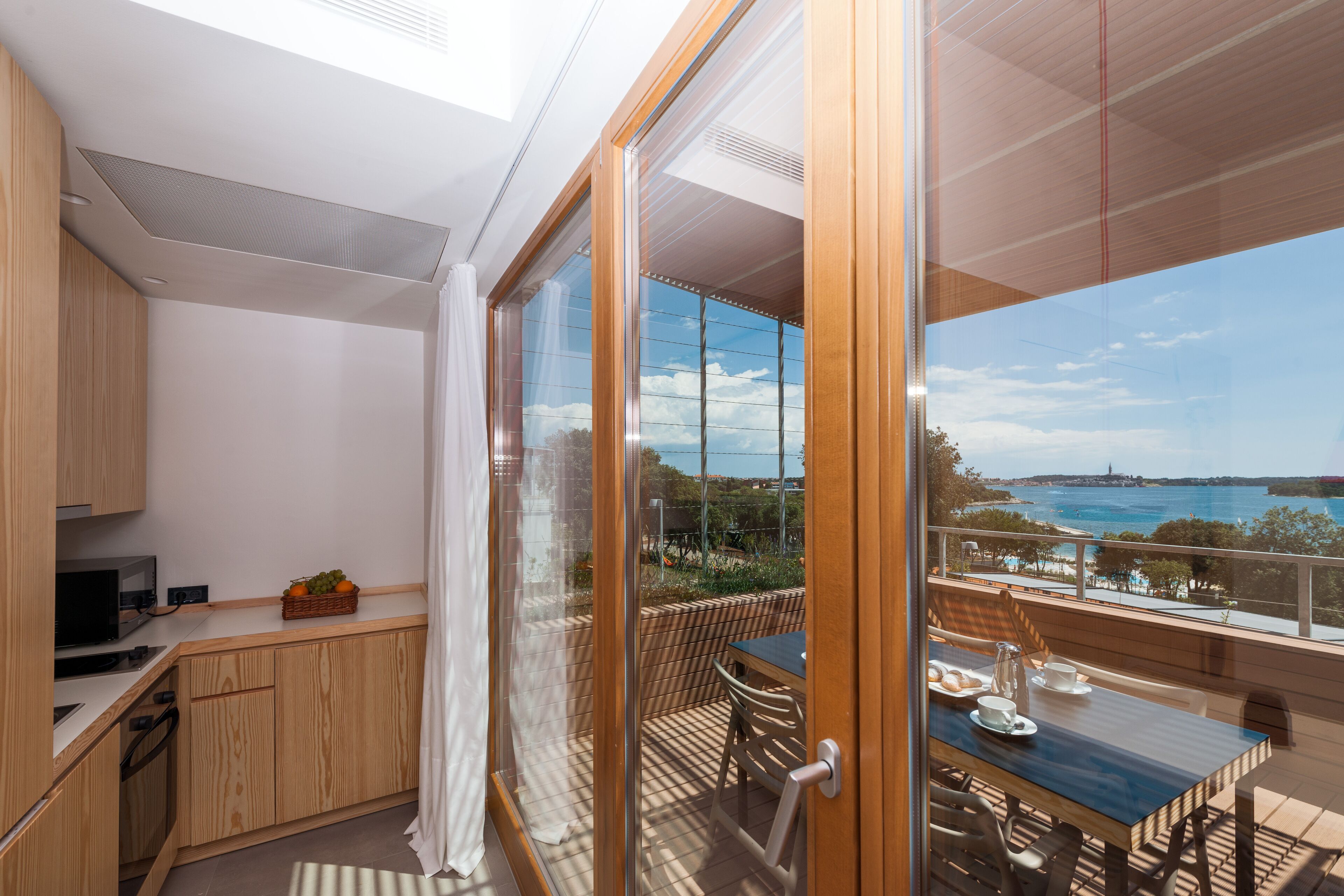 Eine moderne Küche mit Holzausstattung, ein Essbereich mit Tisch und Stühlen und Meerblick.