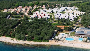 Vue aérienne d’une station balnéaire avec des villas, une plage et une piscine.