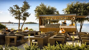 Un espace bar extérieur aménagé avec des meubles en osier et offrant une vue sur la mer.