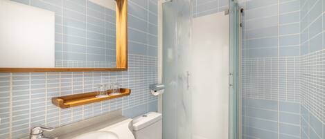Un baño con lavabo, inodoro y ducha con mampara de vidrio.