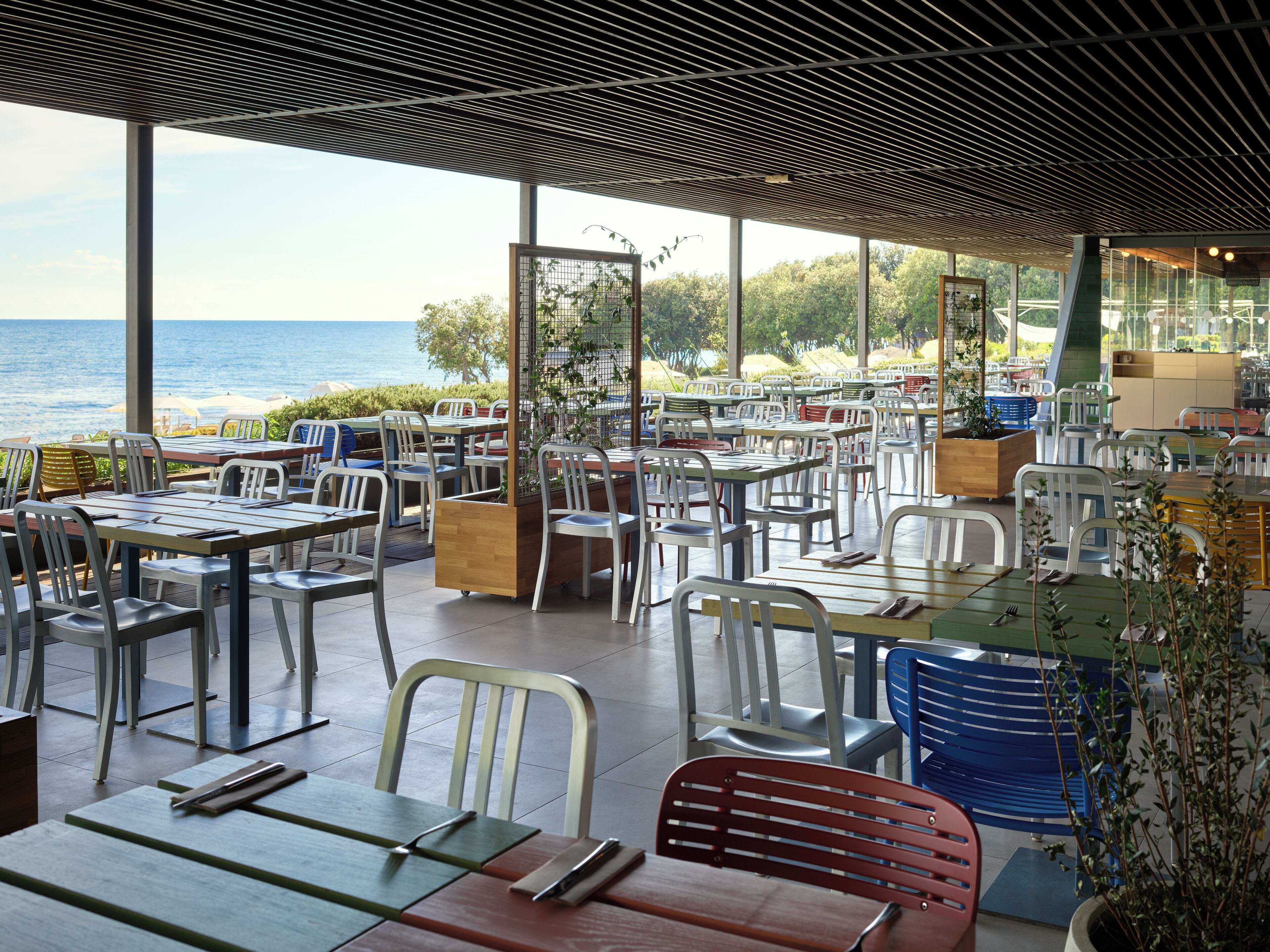 An outdoor dining area with tables and chairs, overlooking a beach.