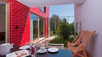 A dining area with a table set for two, a red brick wall, and a view of the garden.