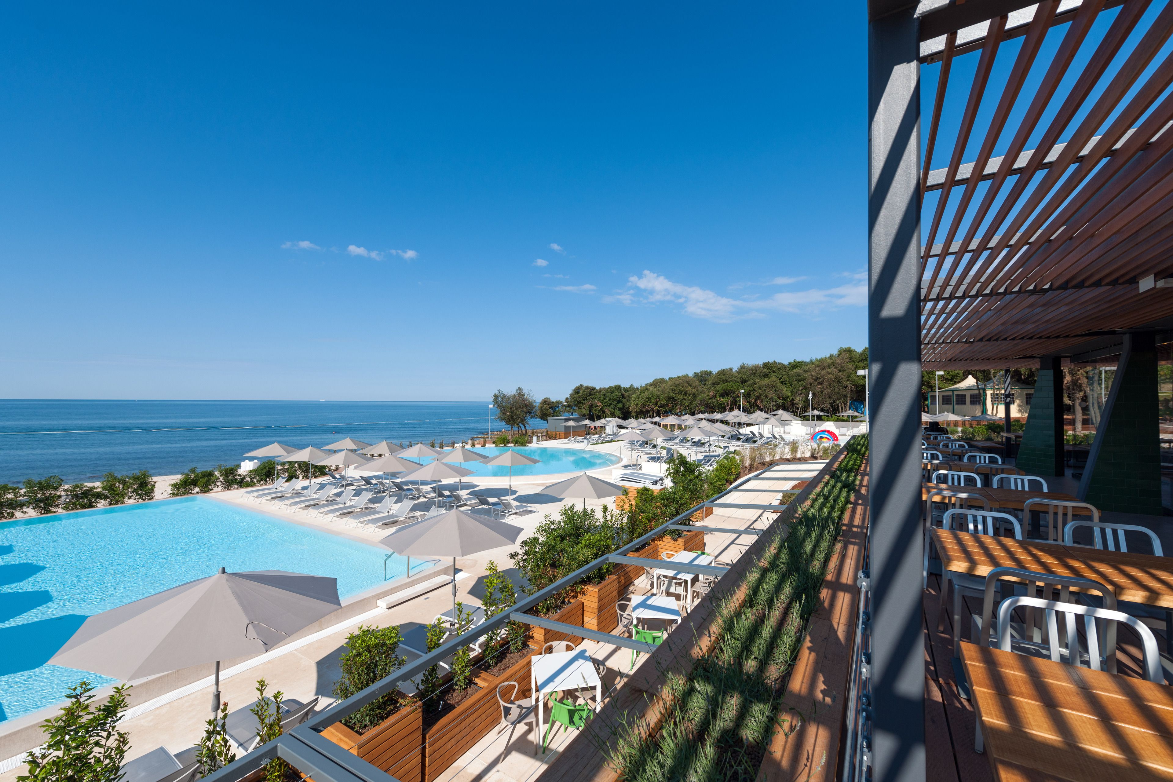 Un complexe hôtelier doté d’une grande piscine, de chaises de plage, de parasols et offrant une vue sur la mer.