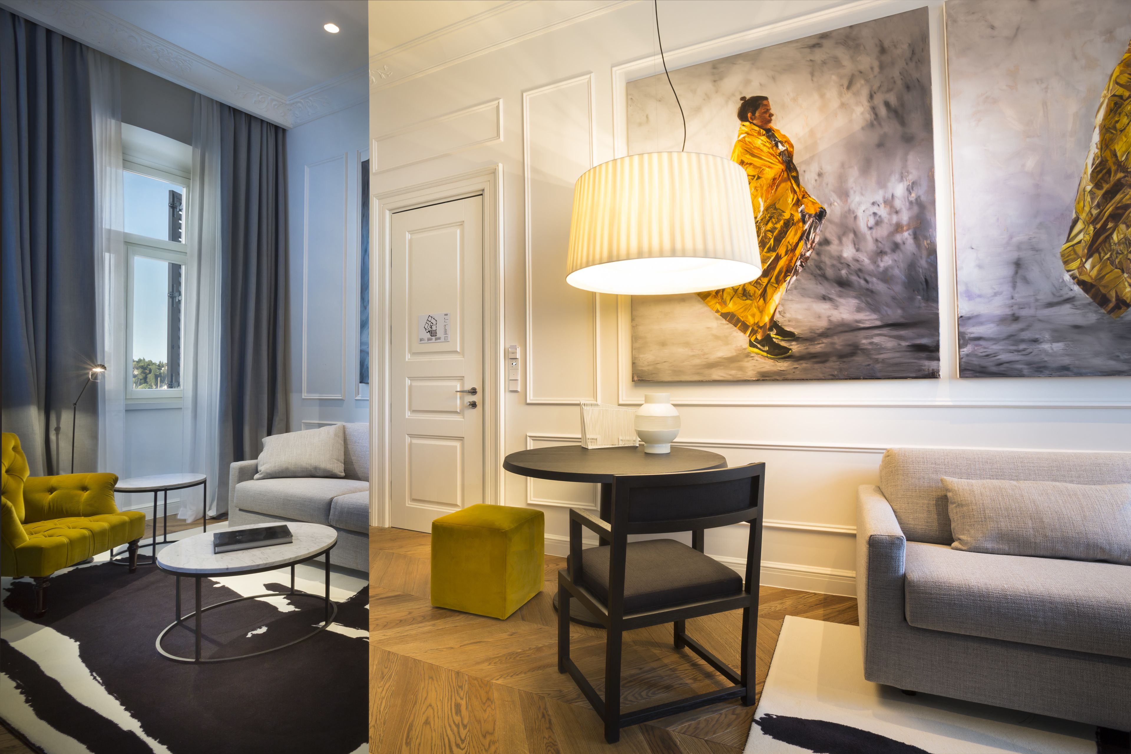Een moderne woonkamer met een bank, fauteuil, poef en een ronde tafel met een lamp.