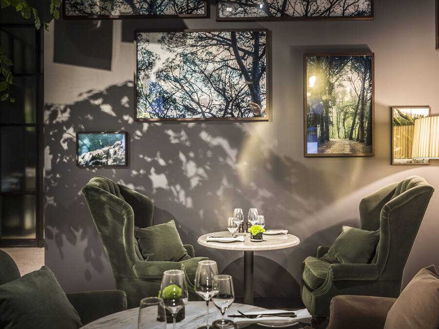 A dining area with a round table set for two, surrounded by green upholstered chairs.