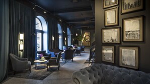 Un moderno hall de hotel con un área de descanso amplia y confortable, grandes ventanales y obras de arte enmarcadas en las paredes.