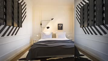 A modern hotel room with a large bed, two bedside tables, a black and white striped wall design, and a mounted picture frame.