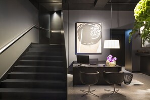 A modern office space with a desk, two chairs, a computer, and a large abstract painting on the wall.