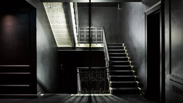 A modern interior with a staircase leading to an upper level, featuring a skylight and a metal railing.