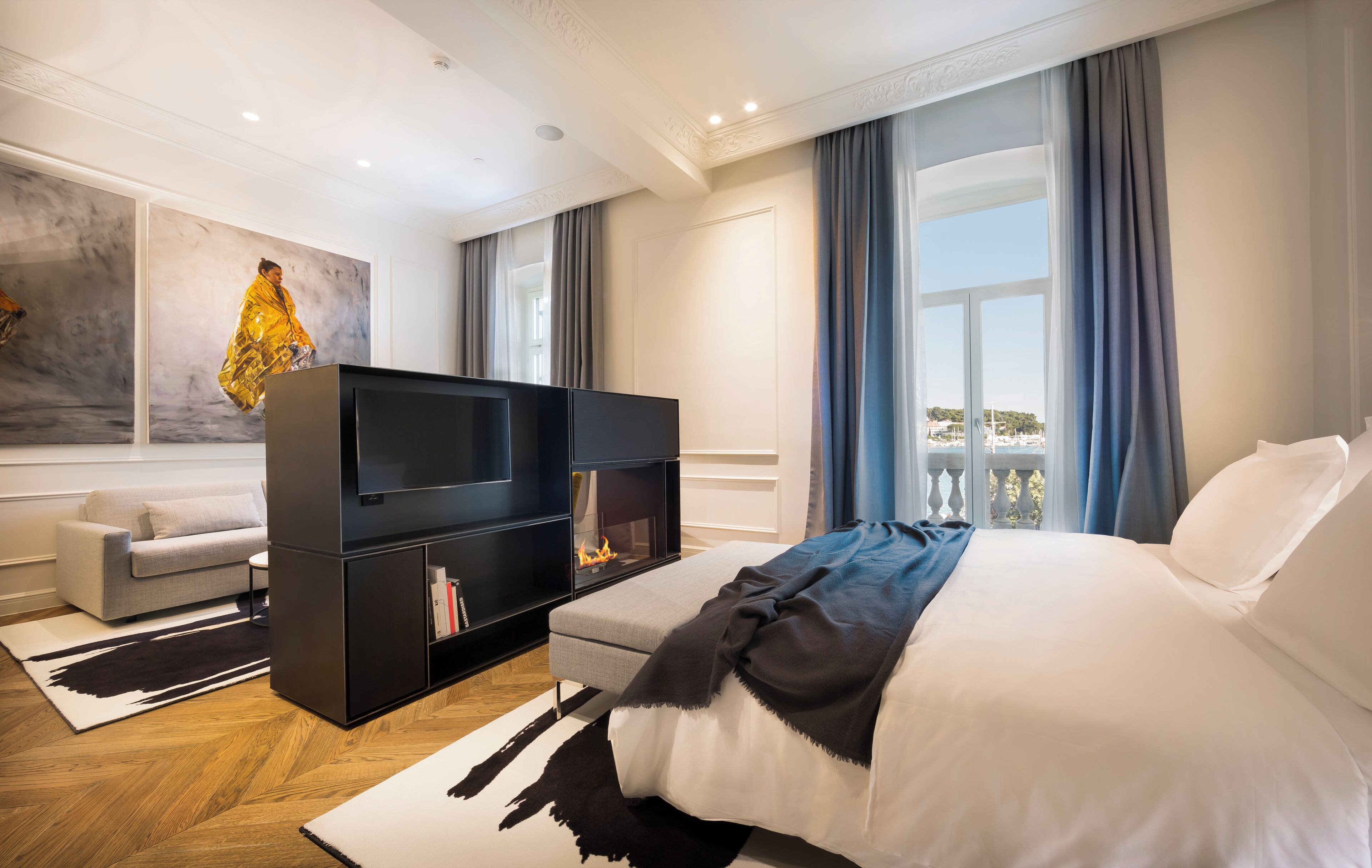 Ein modernes Hotelzimmer mit einem großen Bett, einem Flachbildfernseher, einer Couch und einem Kamin.