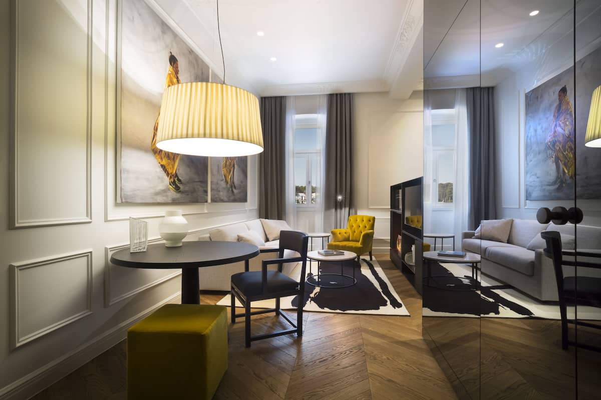 A modern living room with a round table, yellow armchair, and a large lamp.