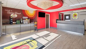 A brightly colored breakfast area with a counter, coffee machines, and a wall with a Super 8 logo. - Super 8 by Wyndham Hazleton (Hazleton)
