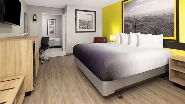 A modern hotel room with a large bed, a desk, and a chair. - Super 8 by Wyndham Hazleton (Hazleton)